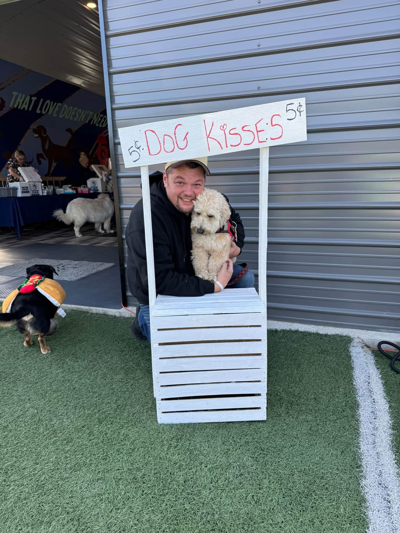 Pack Ride dog kisses booth with Cody and a fluffy guest