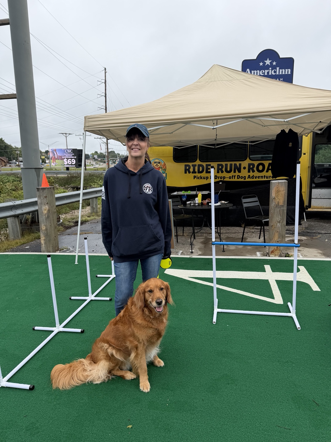 Guest and golden retriever posing by the Pack Ride agility course