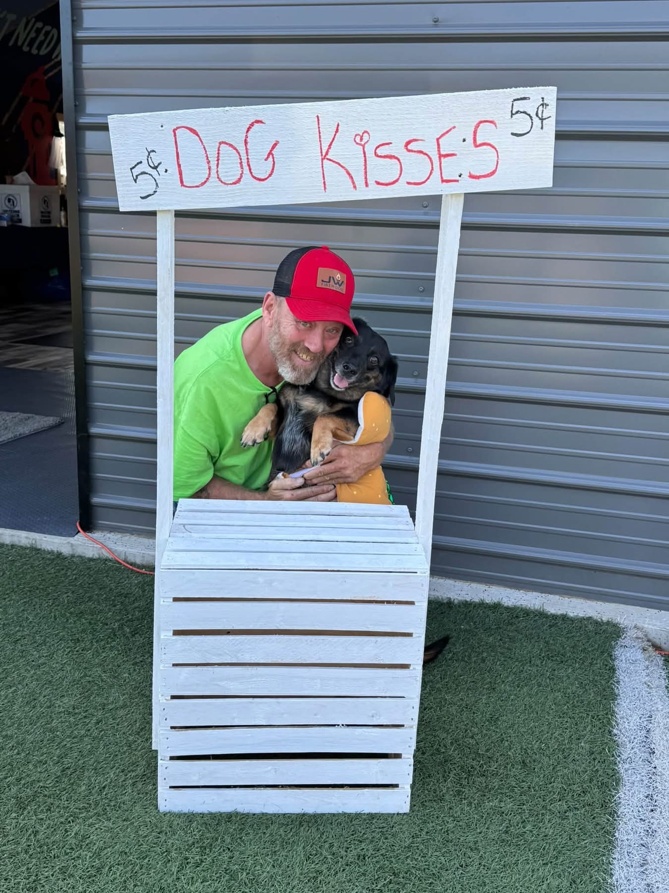 Visitor cuddling a happy dog at the dog kisses booth